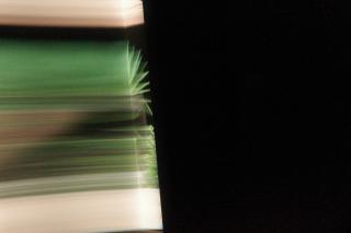 „Ein teilweise verdeckter Blick in einen Raum. Grüne Linien verlaufen entlang der Wände und werden in einer Ecke – ähnlich wie Lichtstrahlen – umgelenkt.