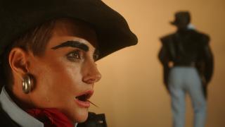 Melanie Jame Wolf, The Creep, 2022 Ein Gesicht im Profil mit Cowboyhut, Ohrringen, gemalten Augenbrauen und offenem Mund mit einem Zahnstocher. Im Hintergrund die Silhouette eines Cowboys von hinten.
