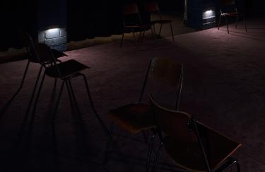 Der Keller in der Filmwerkstatt ist nahezu komplett dunkel. Lediglich ein paar Bodenlampen erhellen den Raum, in den mehrere Holzstühle stehen, um sich KMRUs vierkanalige Klanginstallation anzuhören.